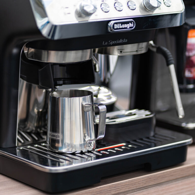 Espressomaschine DeLonghi La Specialista mit Metall-Milchkännchen auf dem Abtropfgitter.